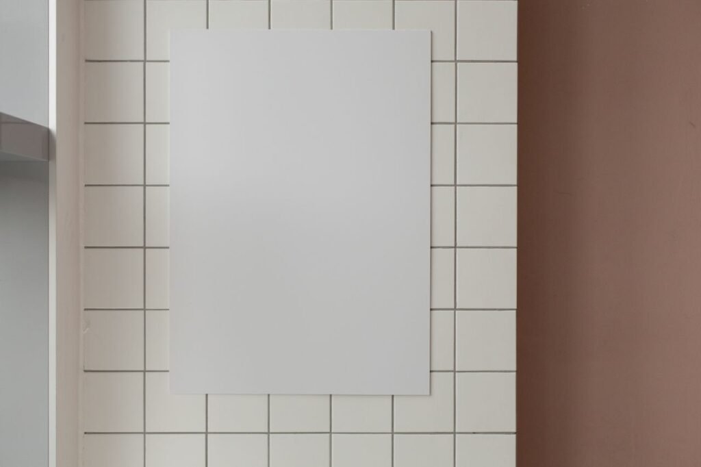 White mock up rectangular poster with copy space hanging on wall with tiles in light room in modern studio